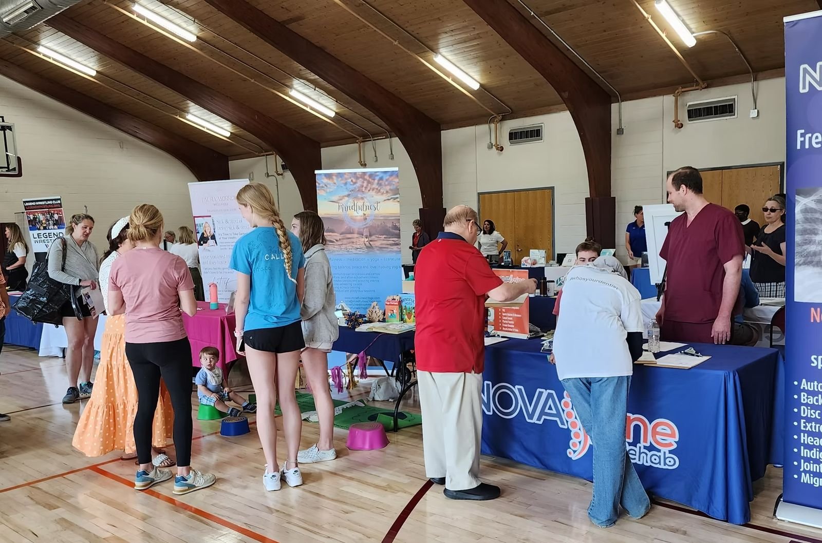 Visitors browsing exhibitor tables in the Vienna Community Center gym