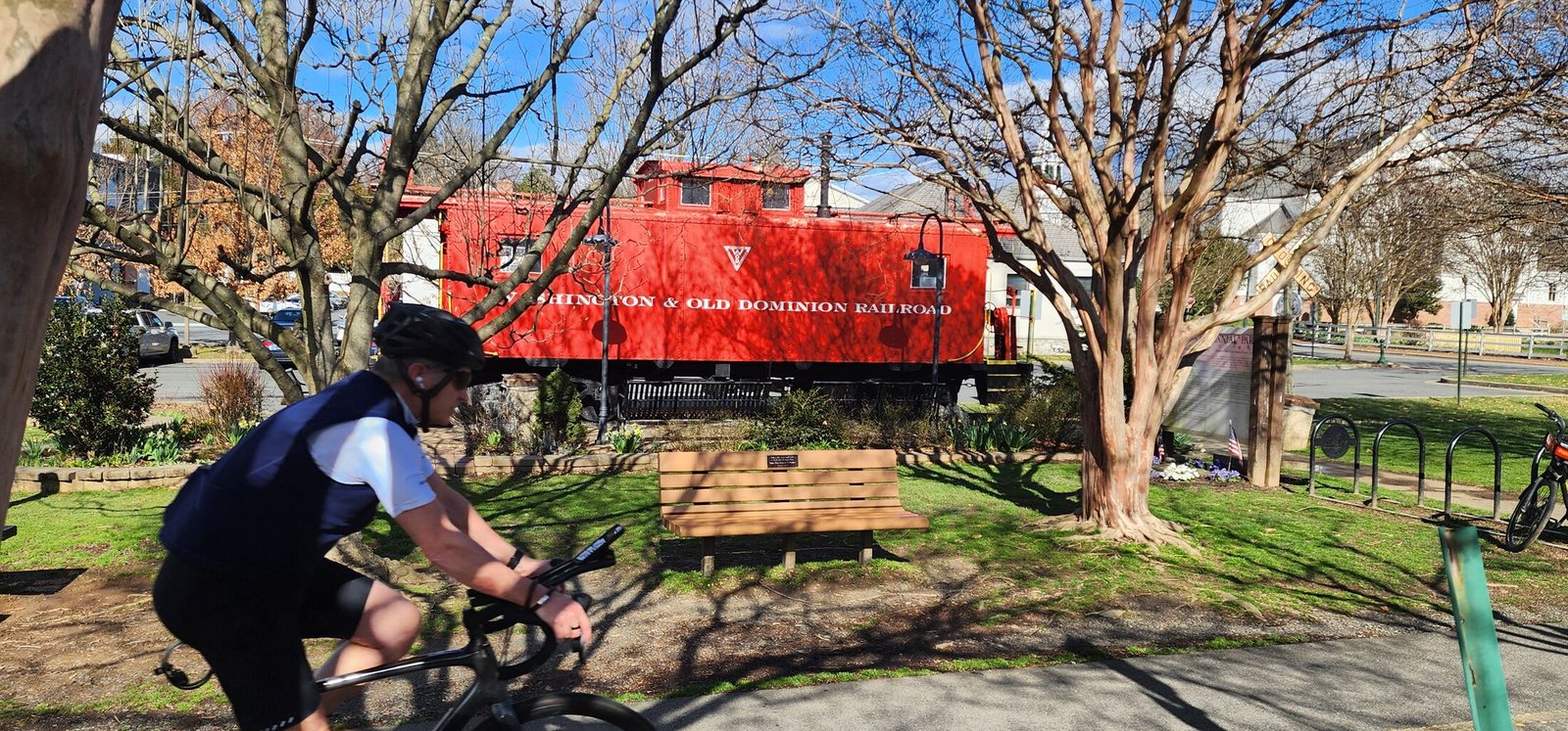 A cyclist rides past the red caboose at Vienna, Virginia's Caboose Park, near the W&OD Trail